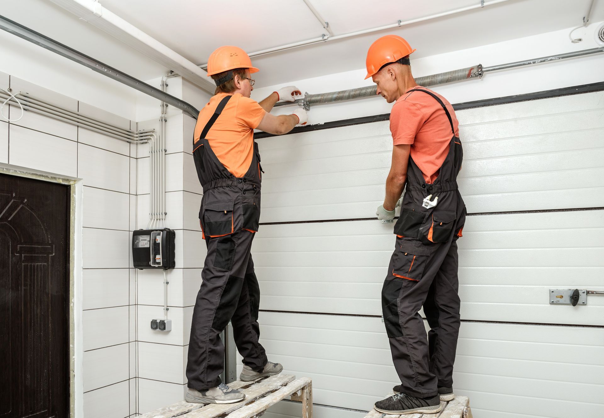 The workers are installing lift gates in the garage.