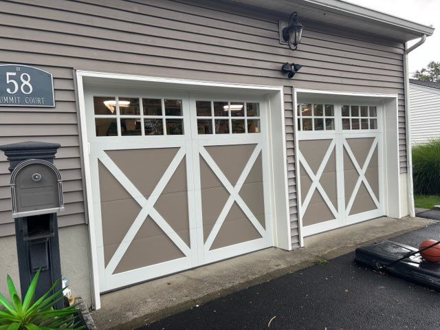 White garage doors with X-bracing on a house exterior beside a dark driveway and mailbox, house number 58.