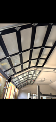 Curved indoor ceiling with black framing and white panels in a bright hallway or atrium