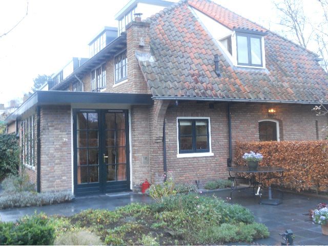 Brick house with red tile roof, dark framed windows, and a covered entrance.