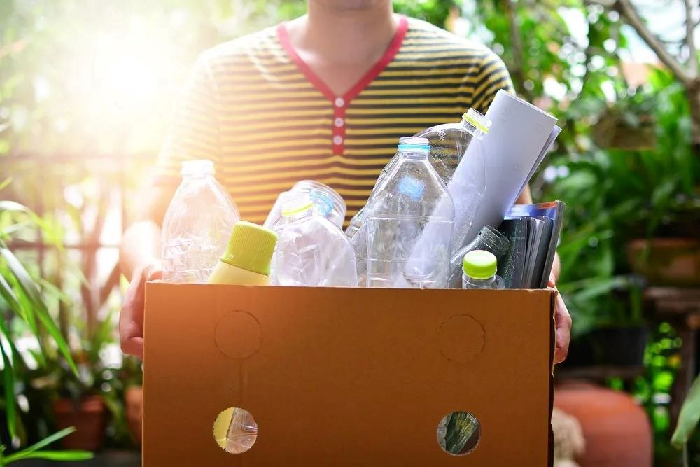 Person holding a box of recyclable cans and bottles in Darwin