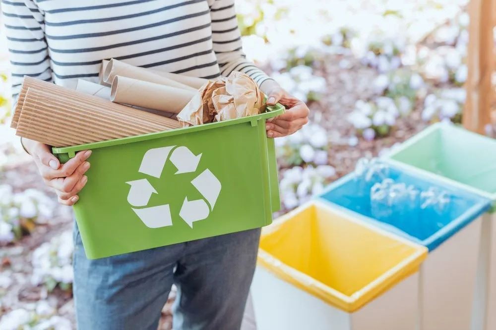 A Woman is Holding a Green Recycling Bin Full of Recyclables — The Territory Can Man In Winnelie, NT