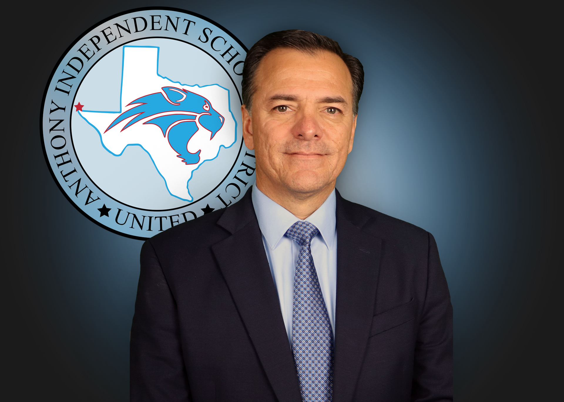 A man in a blue shirt is standing in front of a logo for anthony independent school