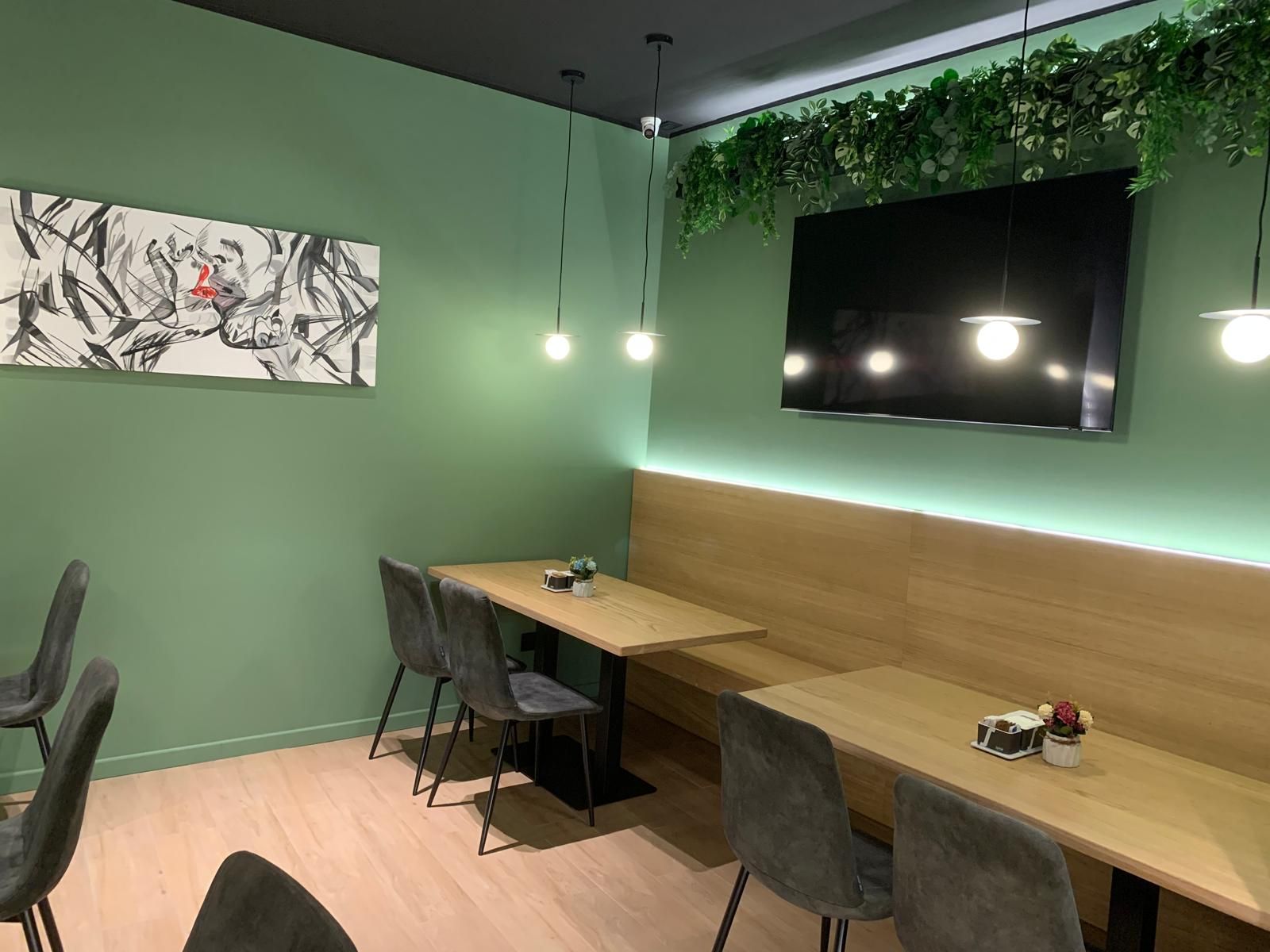 Un ristorante con tavoli e sedie e tv a schermo piatto a parete.