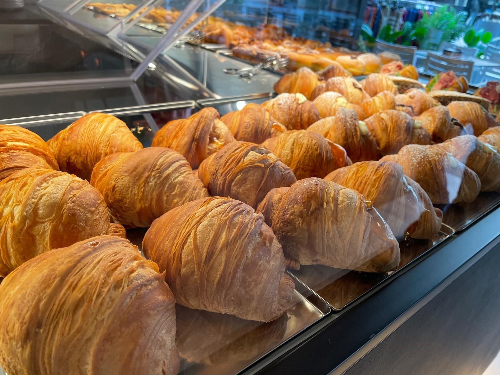 Una vetrina piena di croissant e pasticcini in una panetteria.