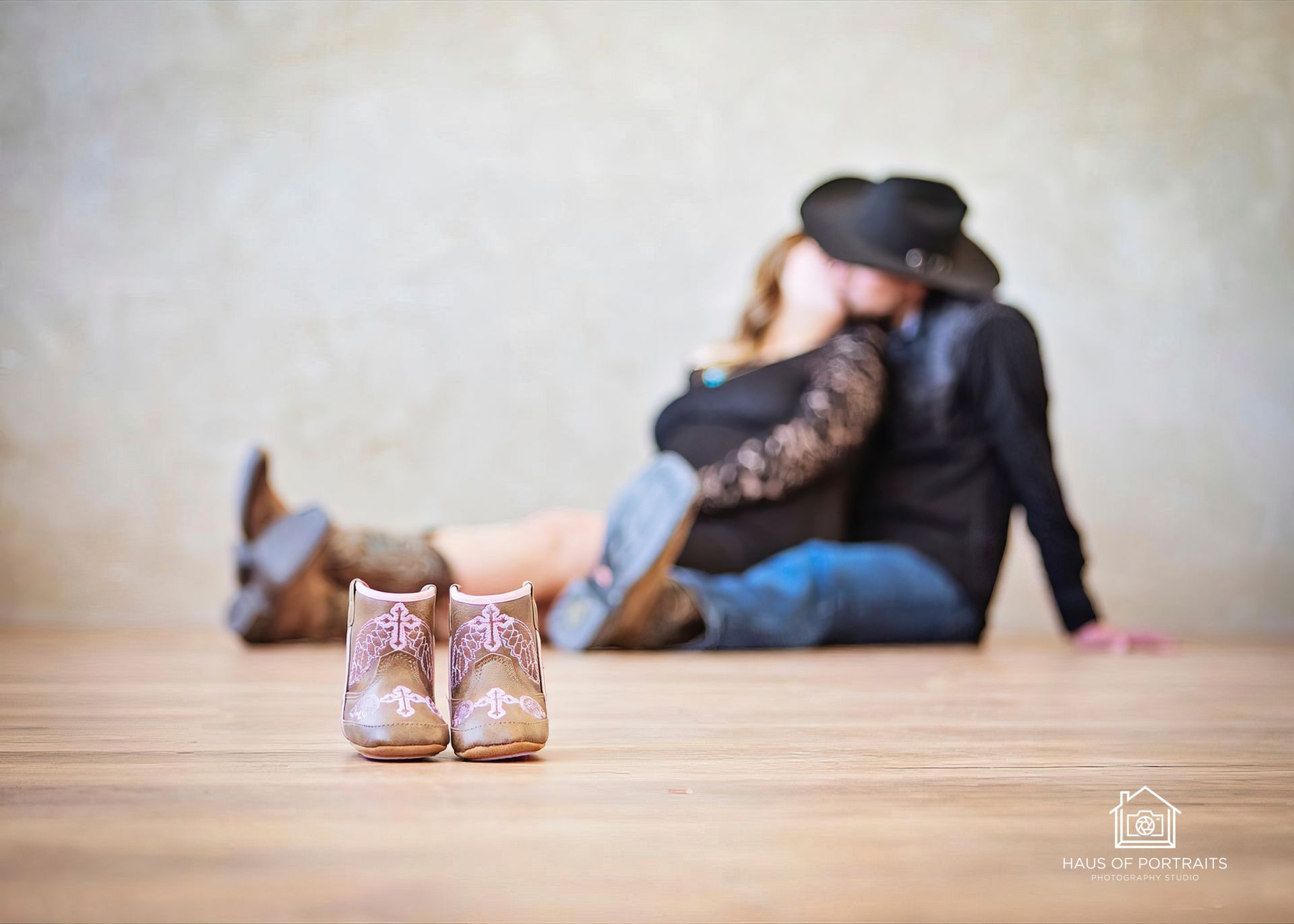Shoes in focus on a wooden floor, with a blurred couple sitting against a wall in the background