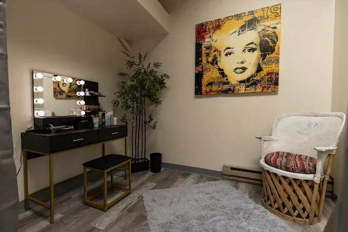 Modern room with vanity, gold table, wicker chair, gray rug, and Marilyn Monroe wall art