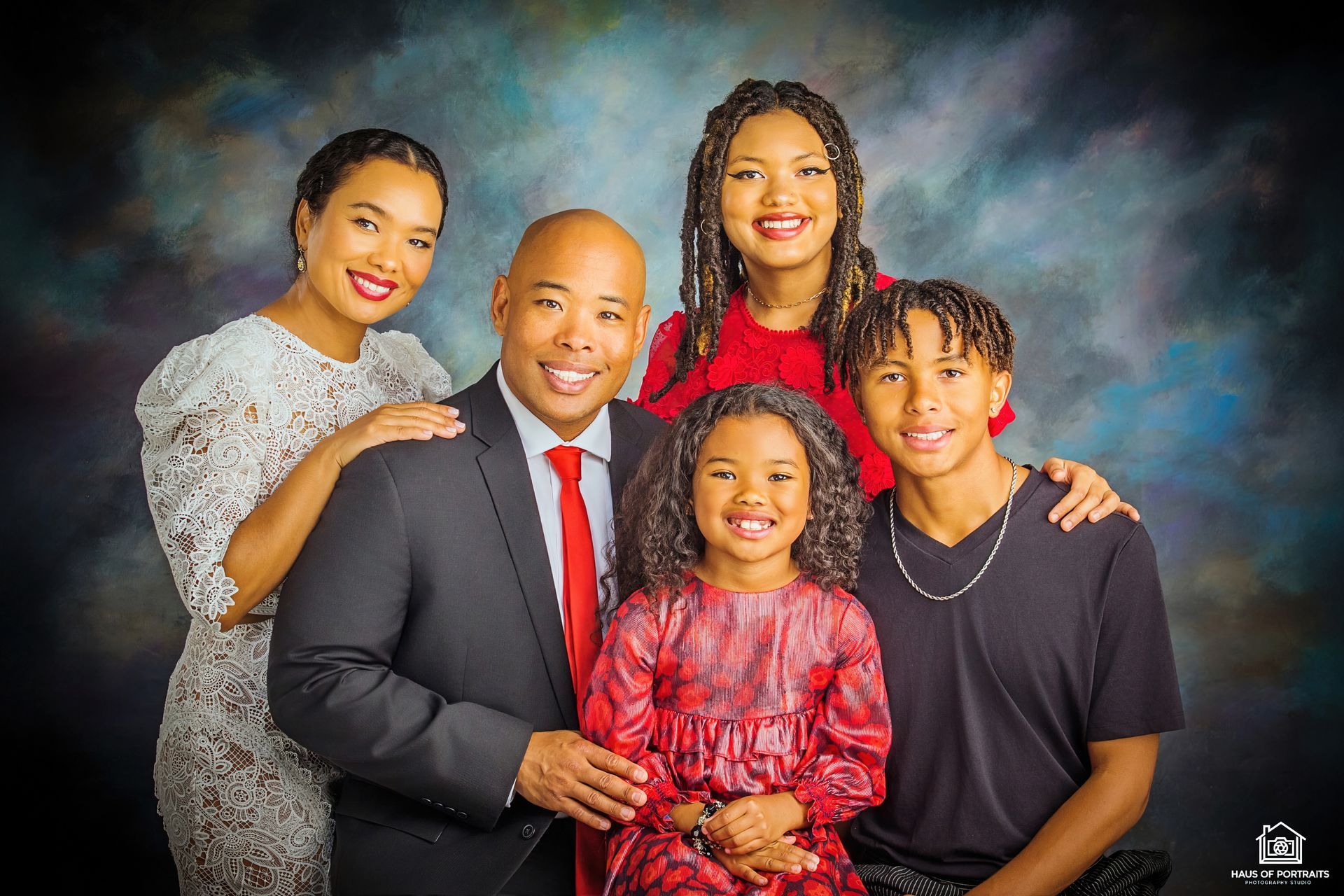 Studio portrait of a smiling family posing together against a painted backdrop