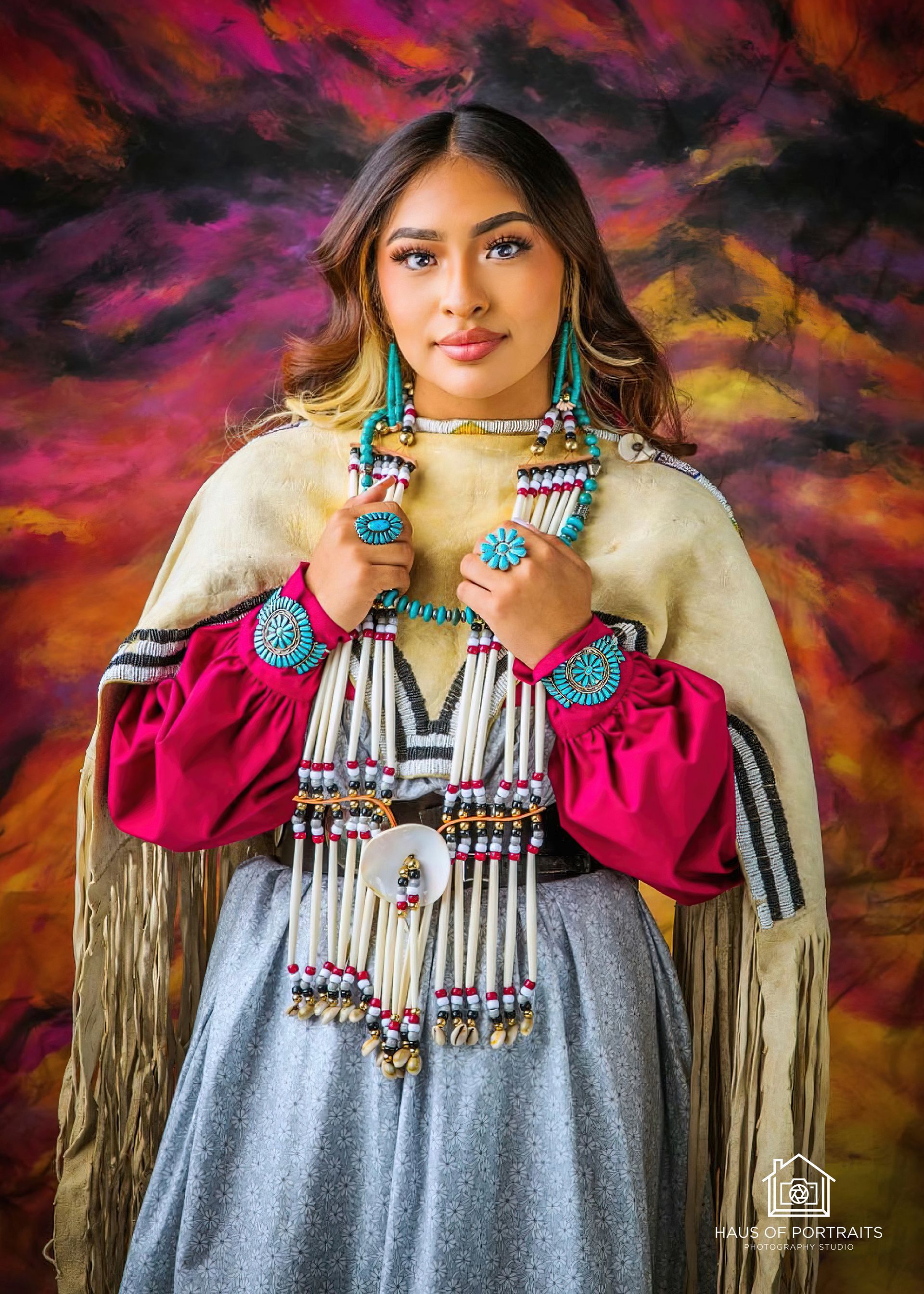 Portrait of a woman in a colorful embroidered dress, wearing jewelry against a dark abstract backdrop