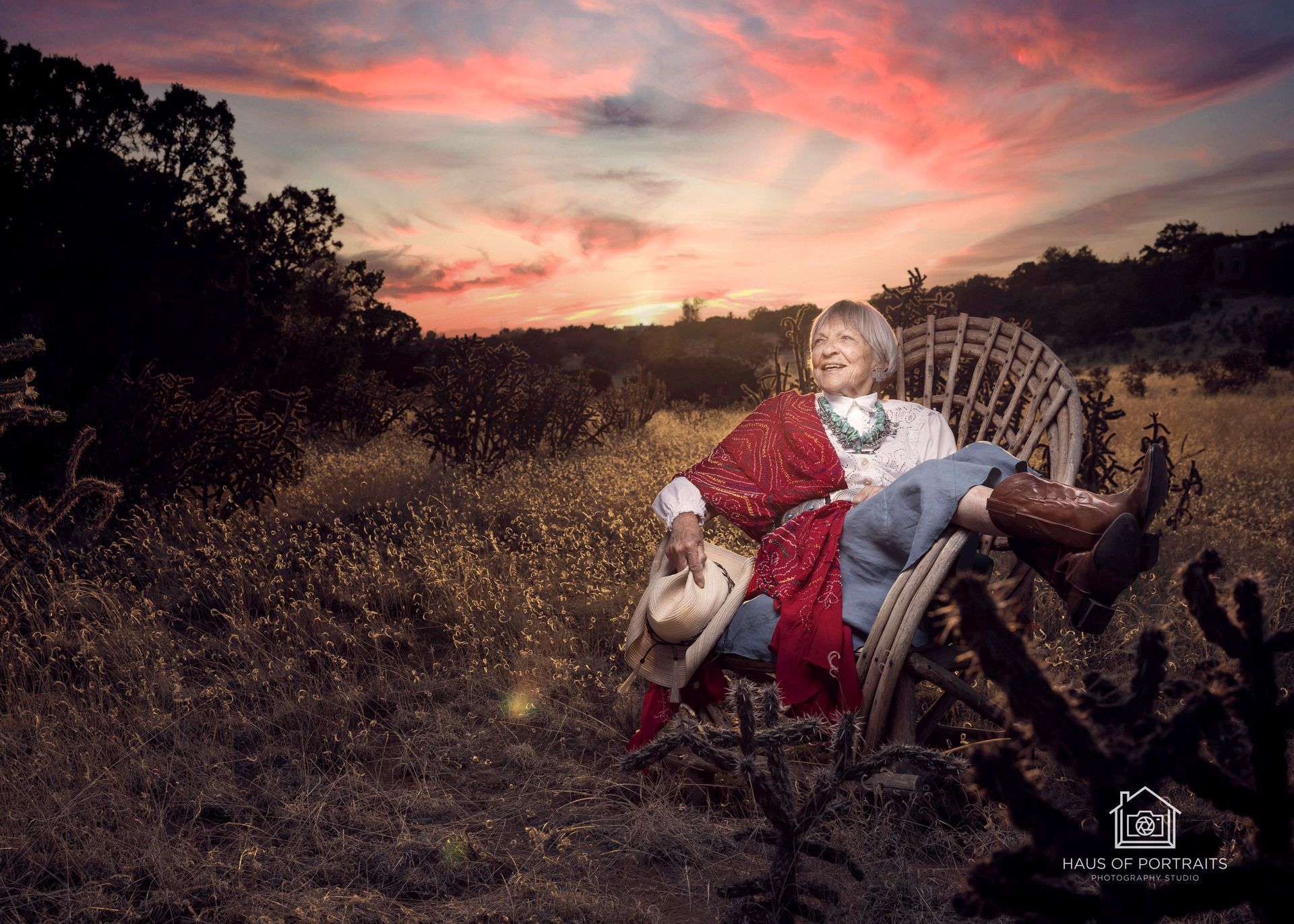 Person in a red outfit reclines in a wicker chair in a grassy field at sunset.