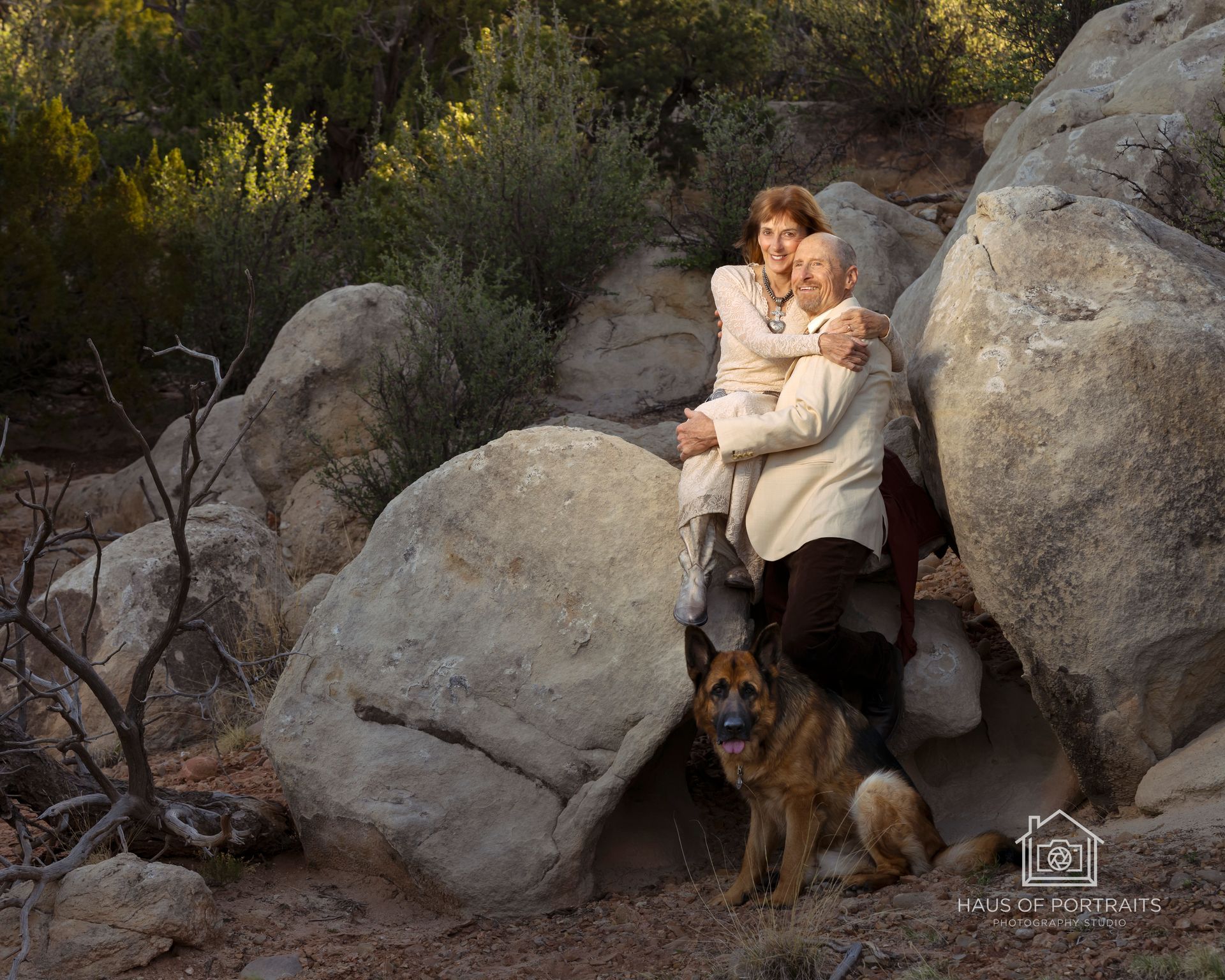 Woman sitting on rocks with a dog in a sunlit, rocky outdoor landscape