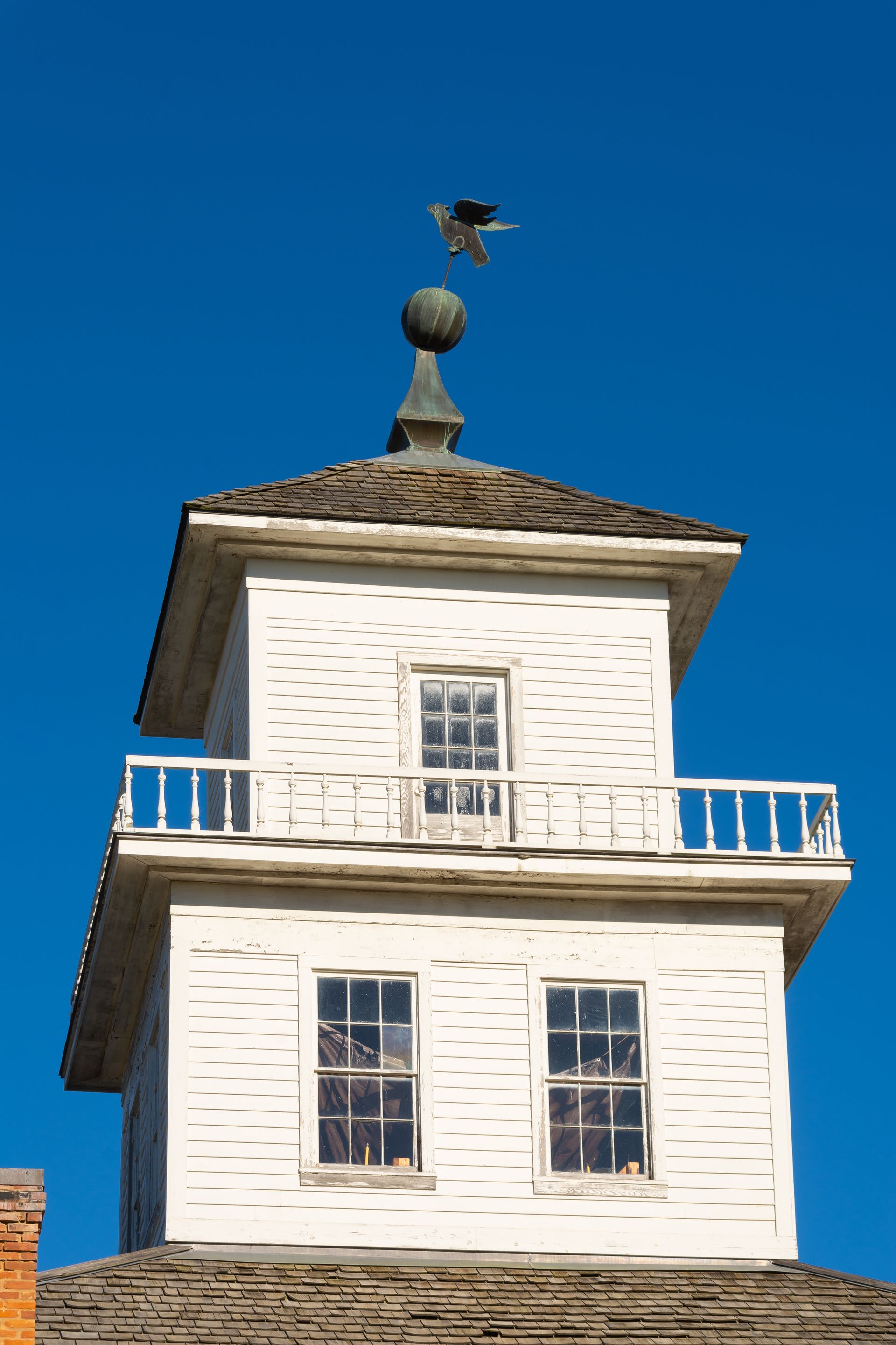 White tower with a weather vane against a clear blue sky