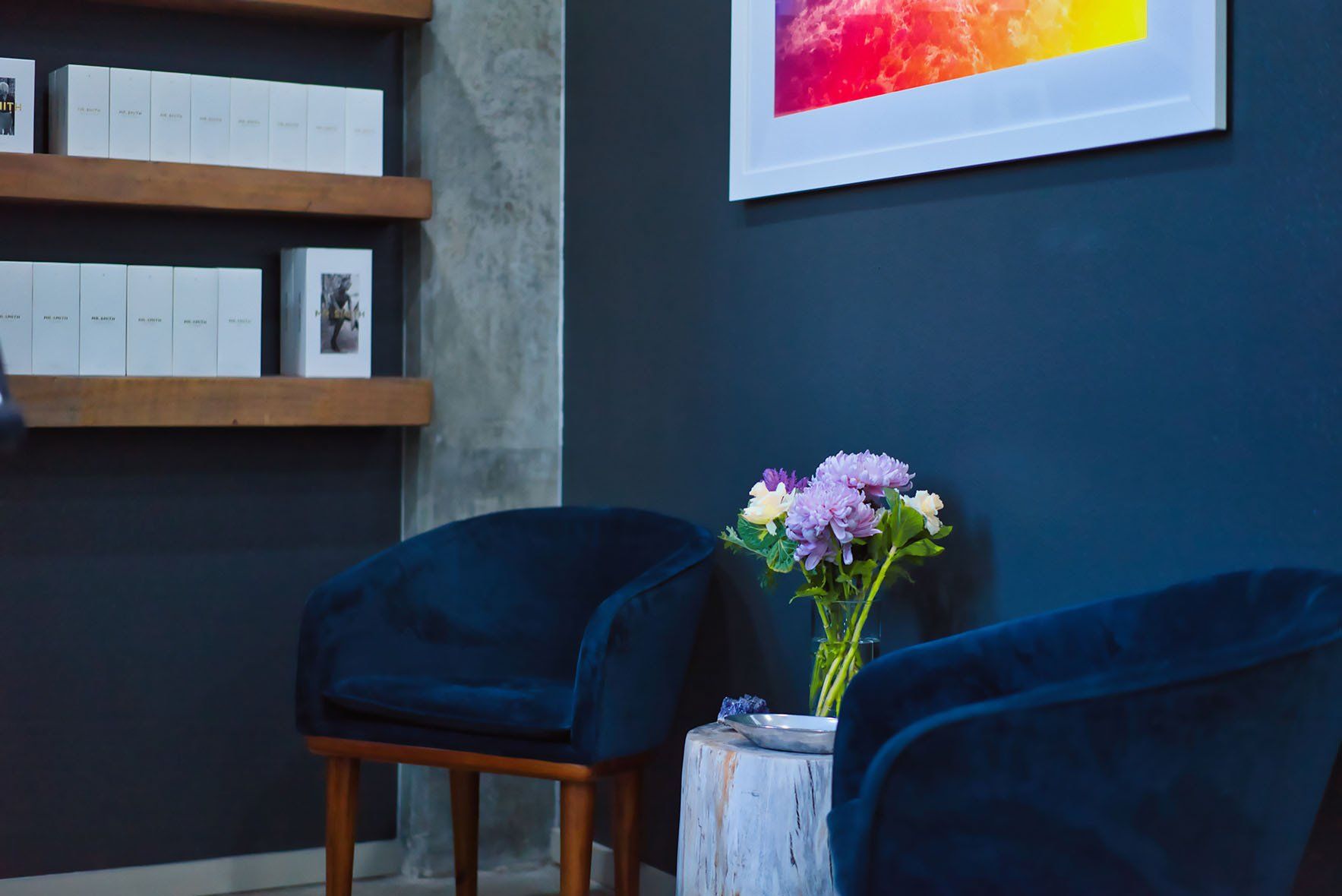 Seating area with blue velvet chairs and purple flowers