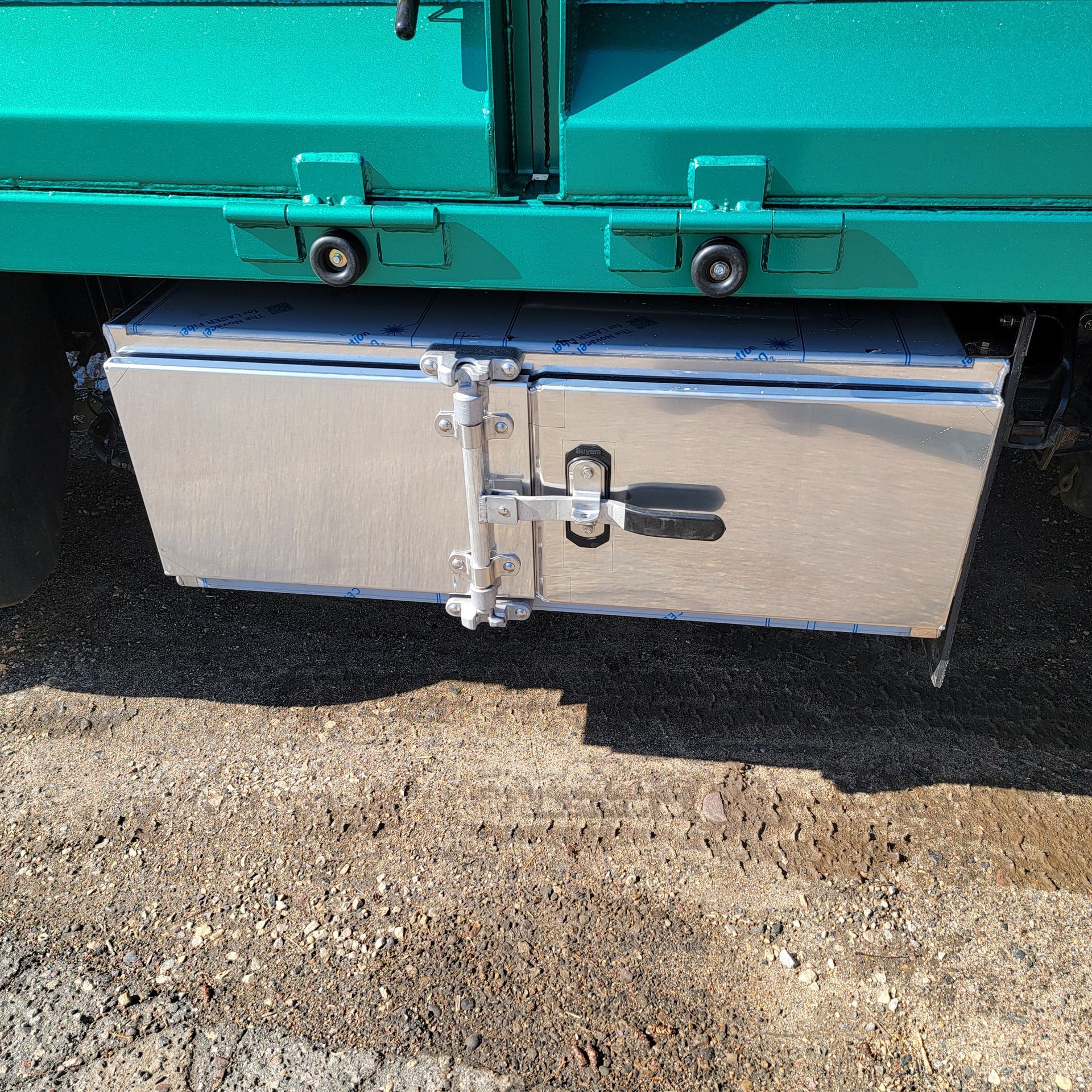A green truck with a silver box underneath it