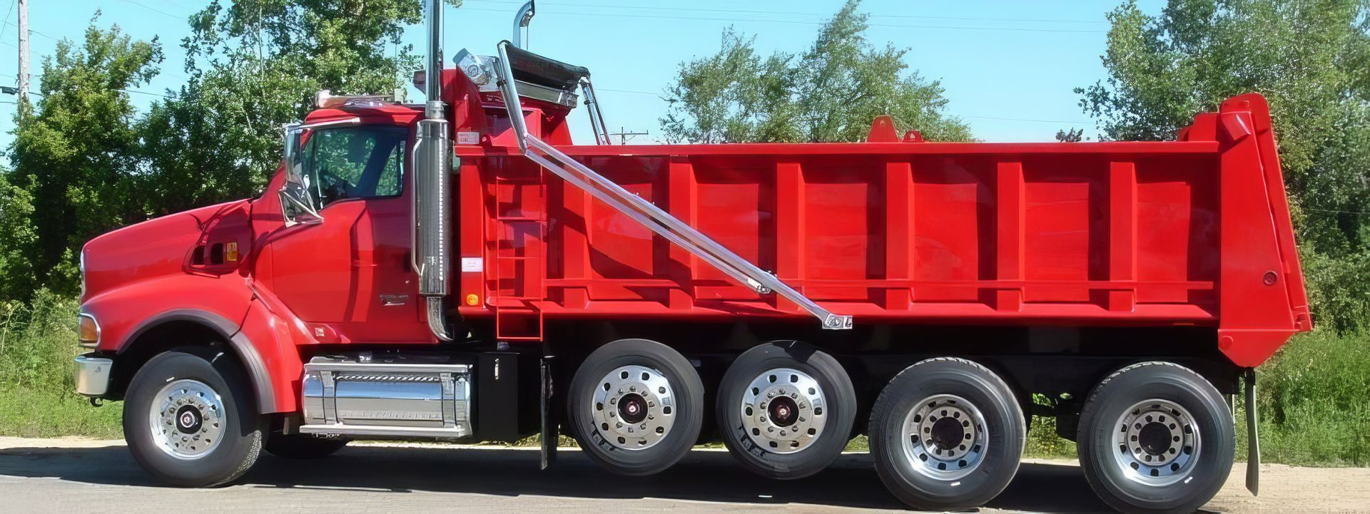 A red dump truck is parked on the side of the road