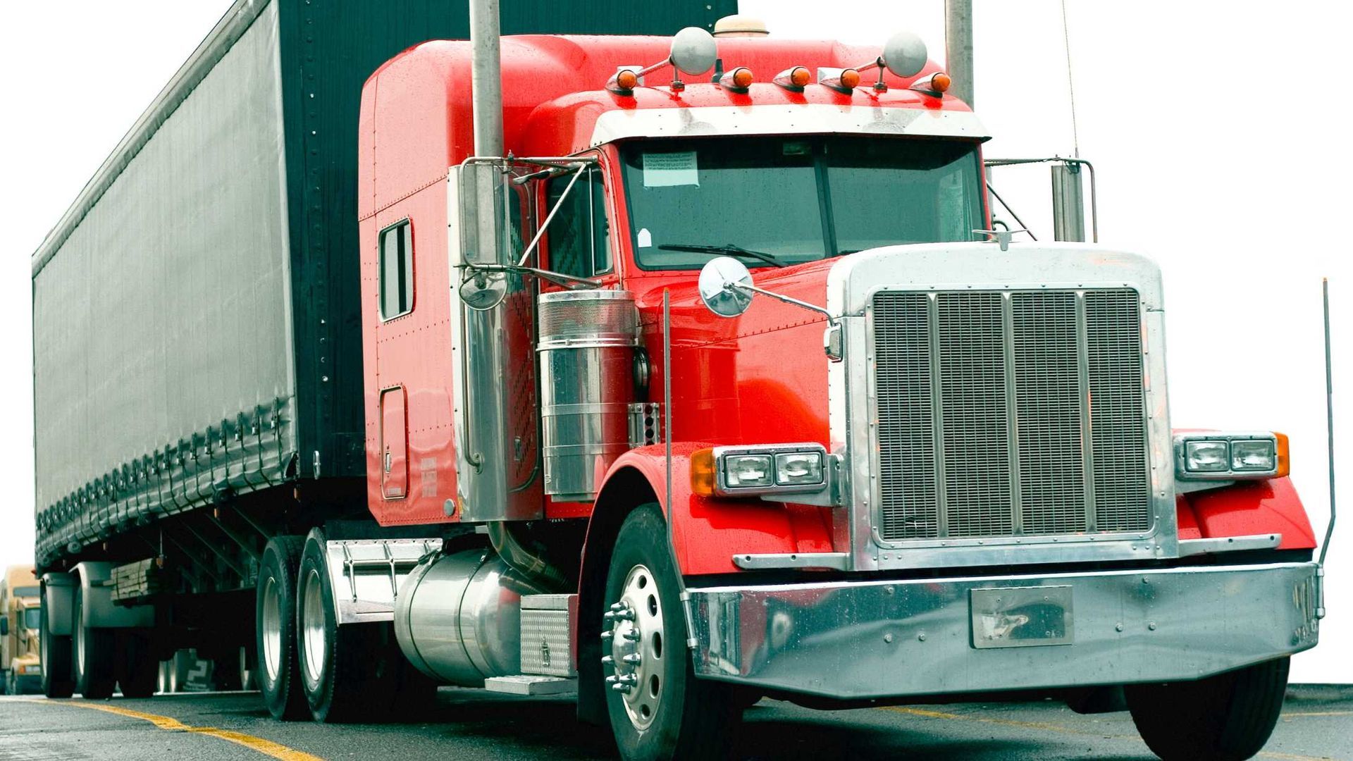 A red semi truck is parked on the side of the road