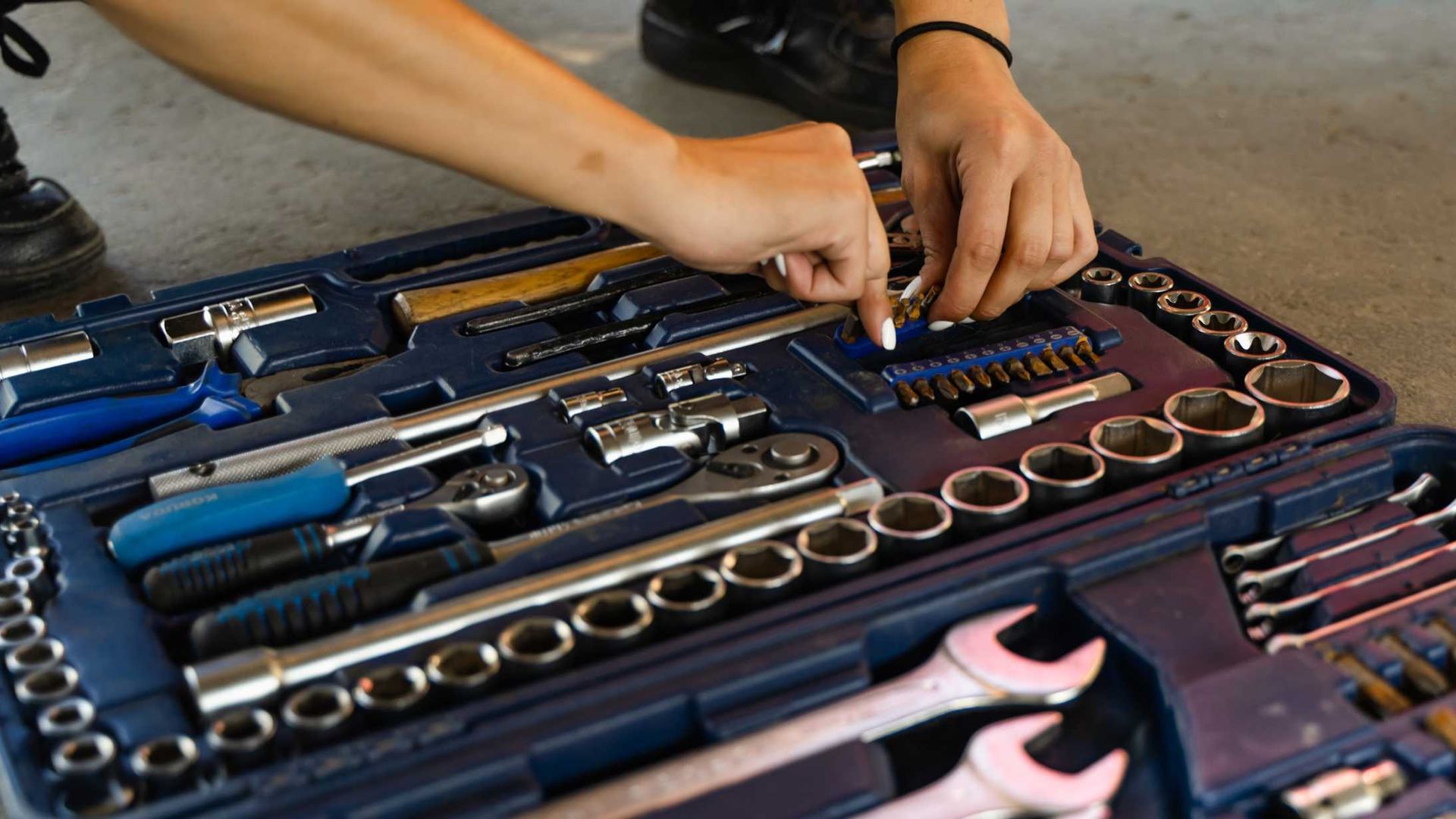 A person is working on a toolbox filled with tools.