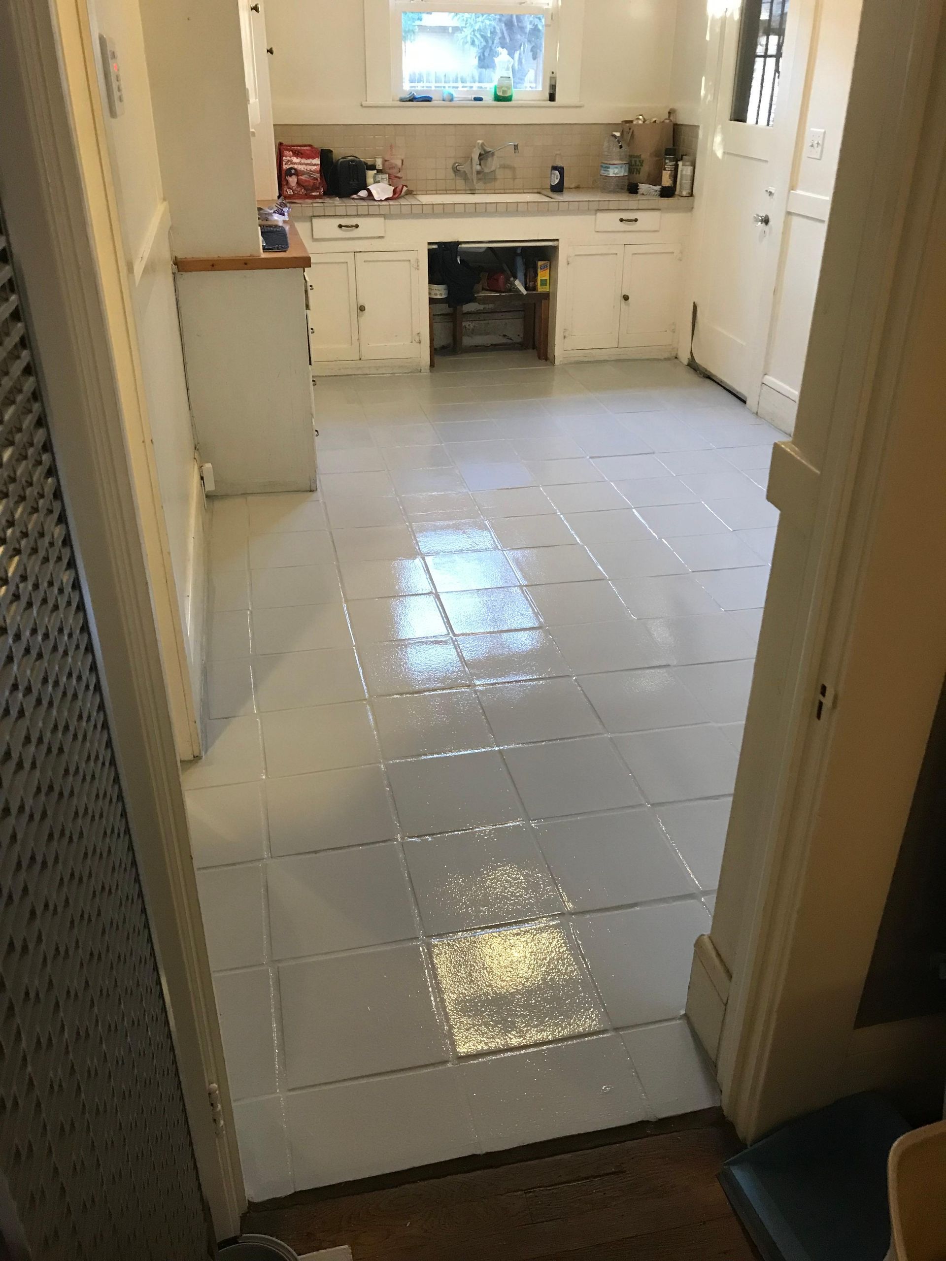 A kitchen with white cabinets, a light gray floor, and a window above the sink.