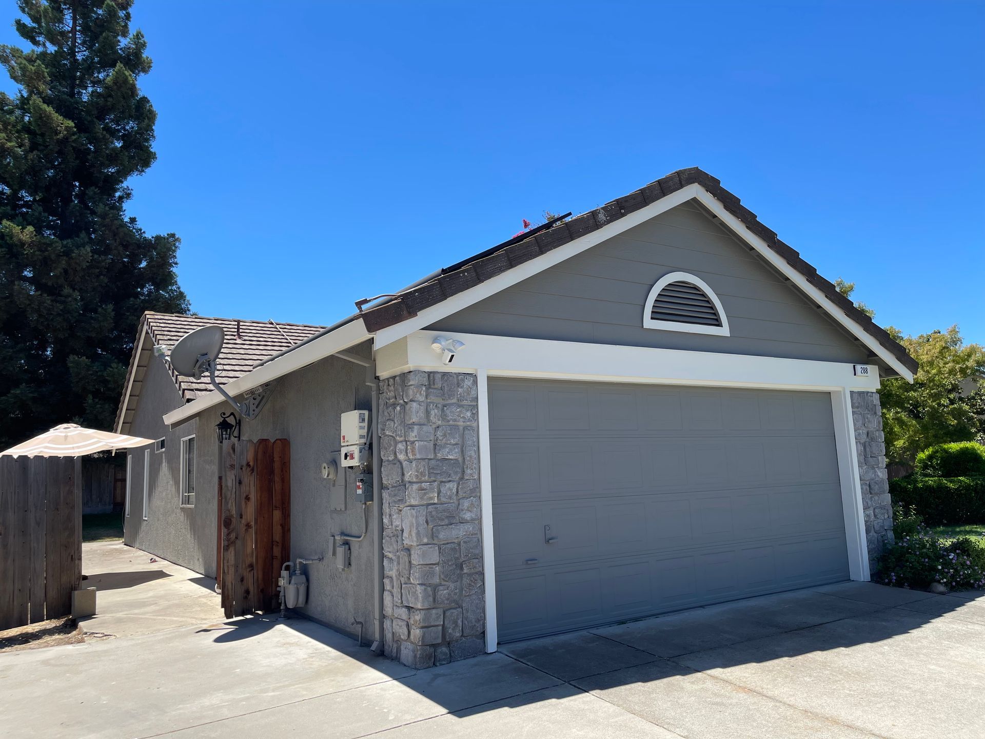 Gray garage with stone accents, gray door, under a blue sky.
