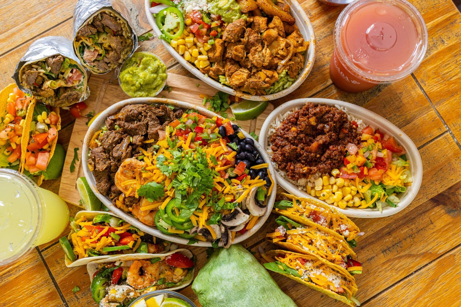 a wooden table topped with bowls of food and drinks.