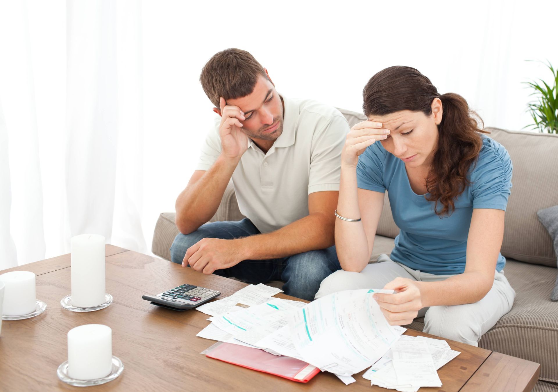 Couple looking distressed at bills on a table.