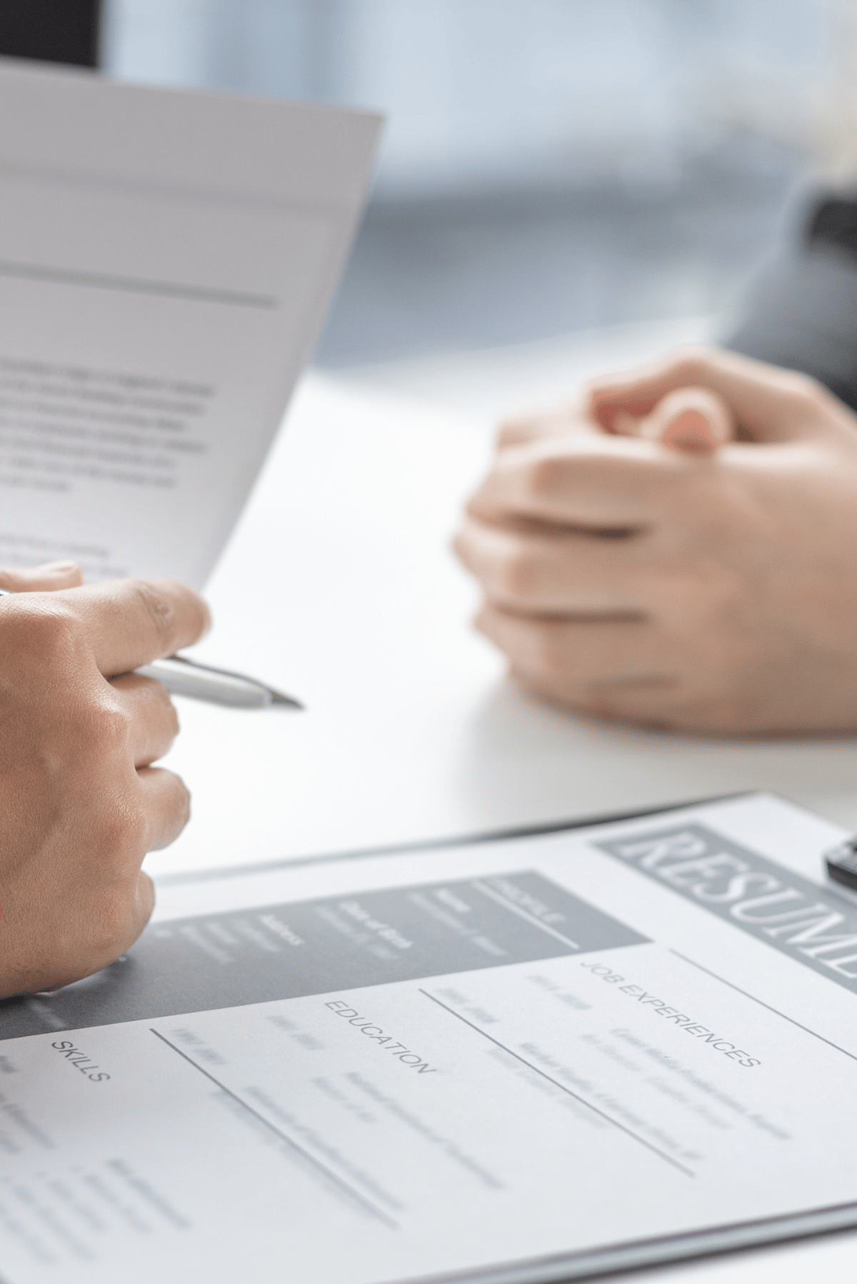 Hands reviewing documents on a desk with a pen and paperwork in a business meeting