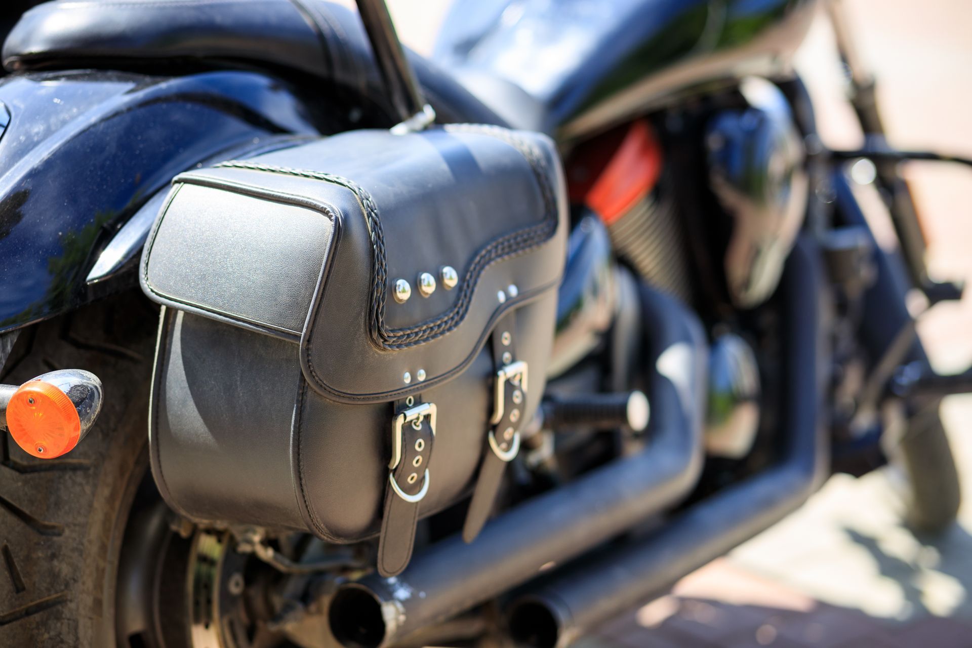 Black motorcycle saddlebag with buckles on a parked bike