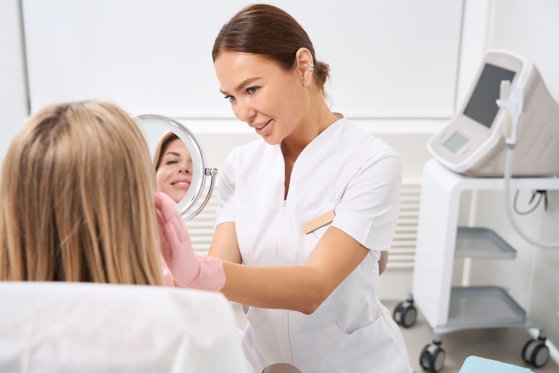 A woman is looking at her face in a mirror.