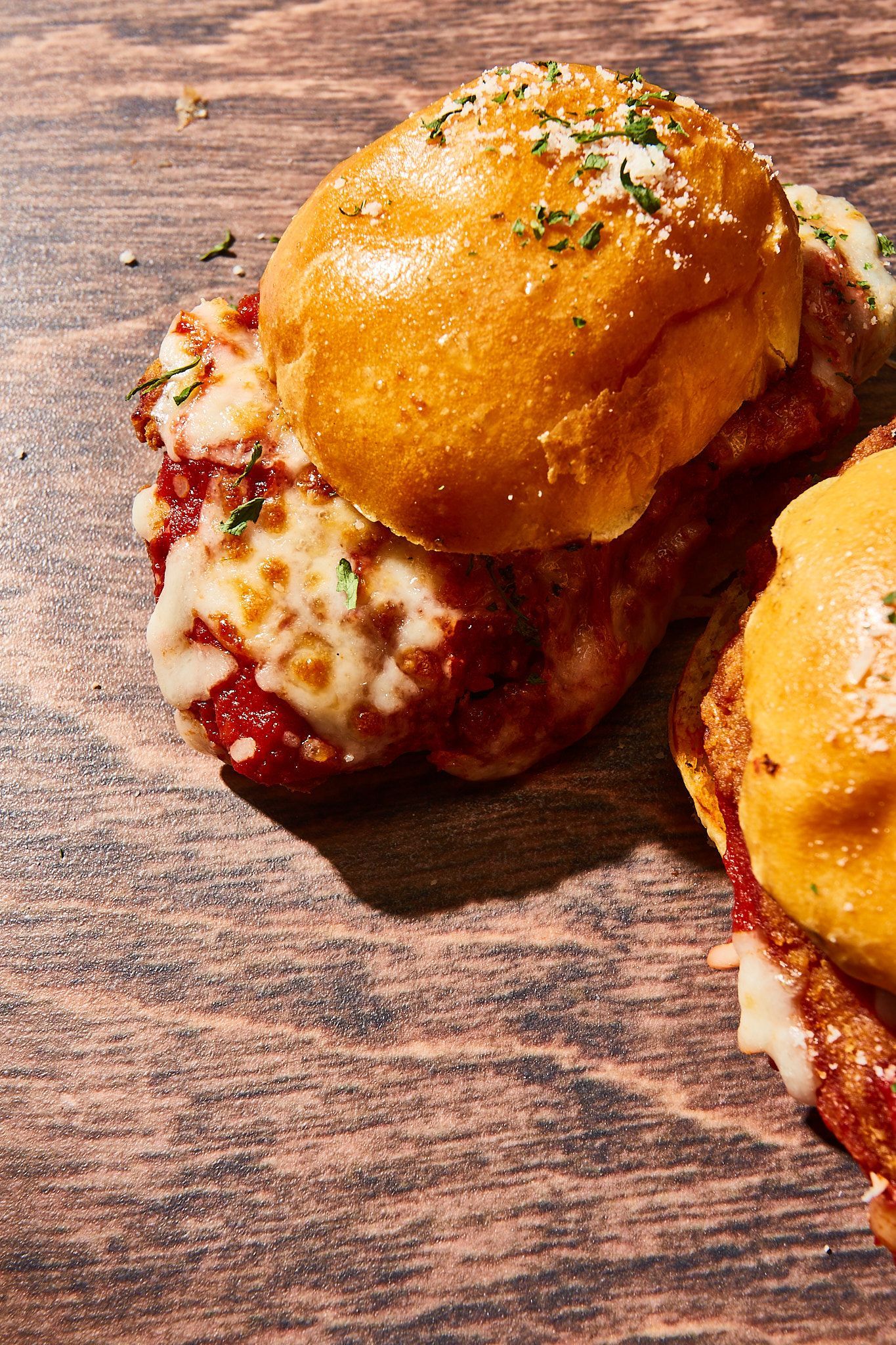 A close up of two meatballs sliders on a wooden table.