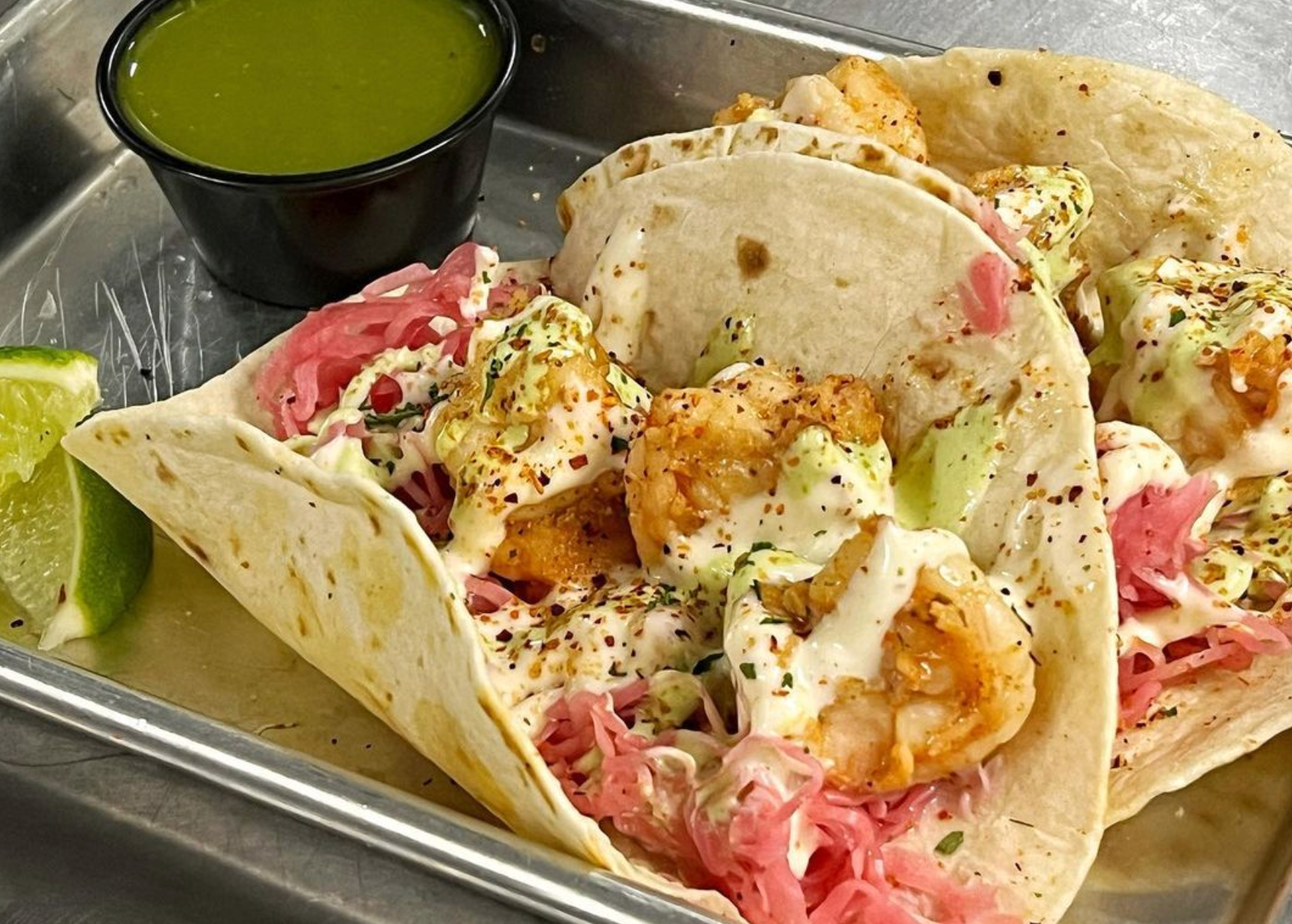 A close up of a taco on a tray with a side of dipping sauce.