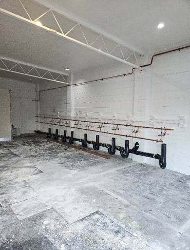 A large empty room with a lot of pipes on the wall.