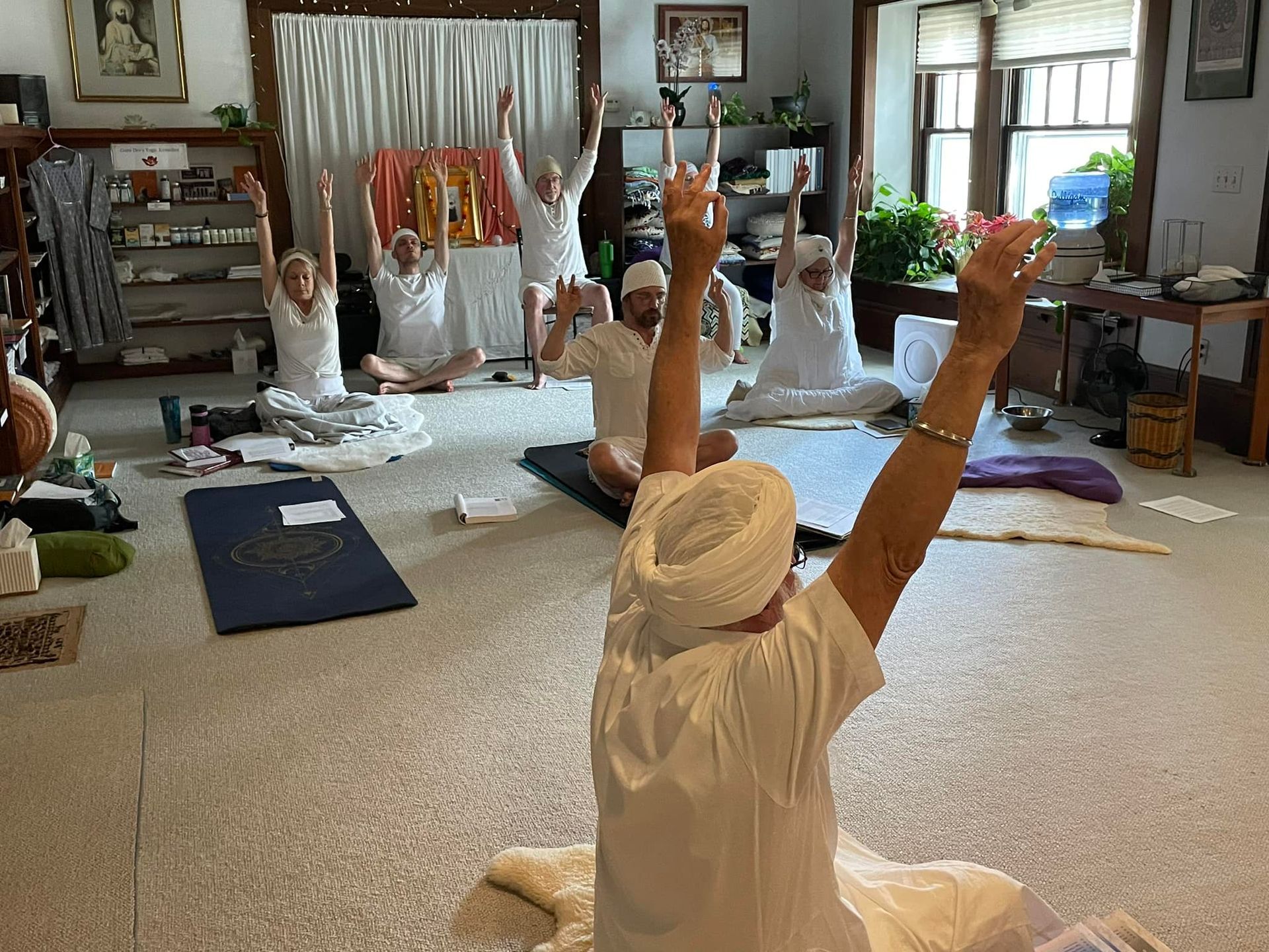 A group of people are sitting on the floor with their arms in the air.