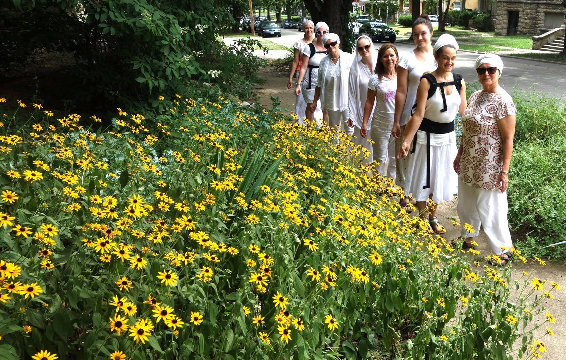 A group of women are walking through a field of yellow flowers.