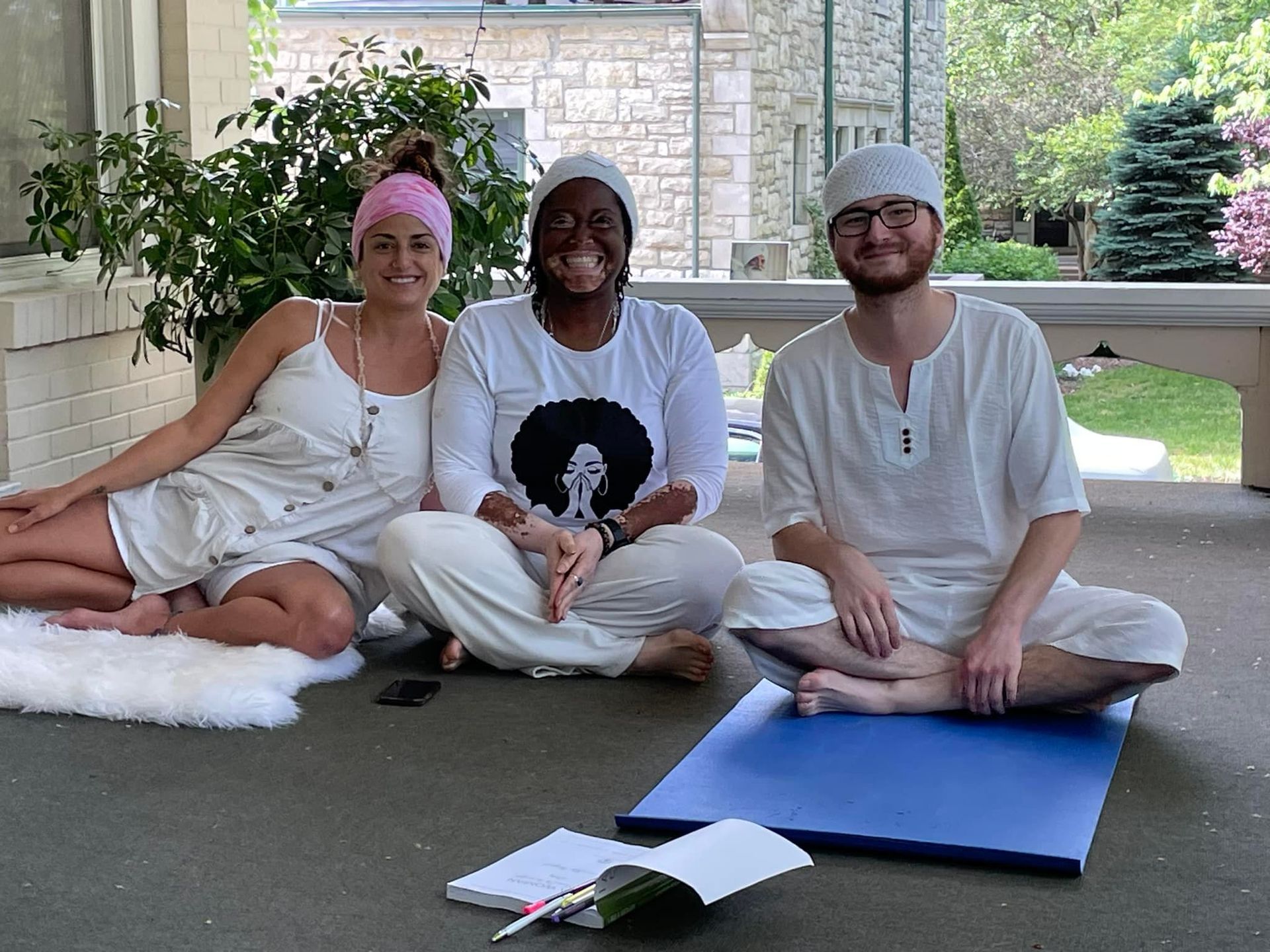 A man and two women are sitting on a yoga mat