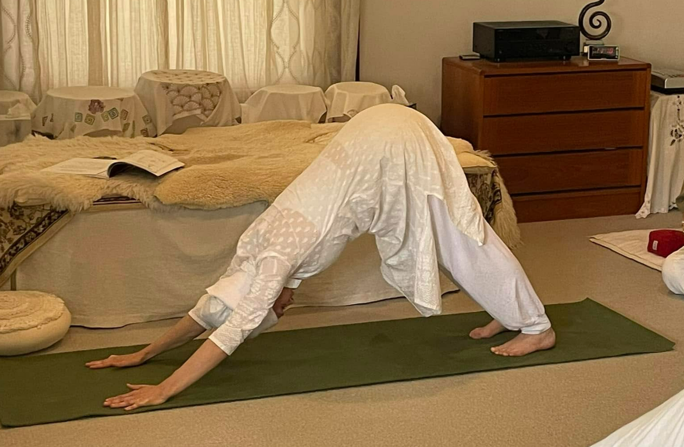 A person is doing a yoga pose on a mat in a bedroom.