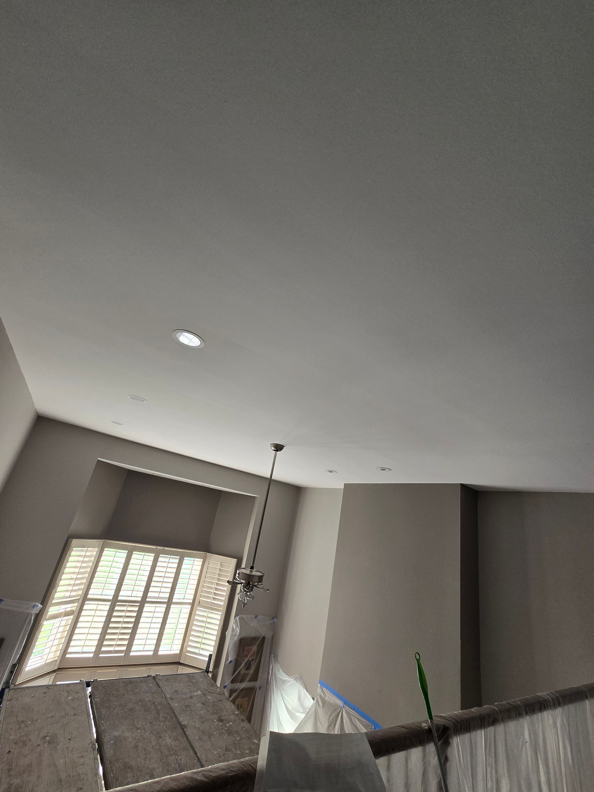 Stairwell with gray walls, ceiling light, and a window with white blinds above the stairs