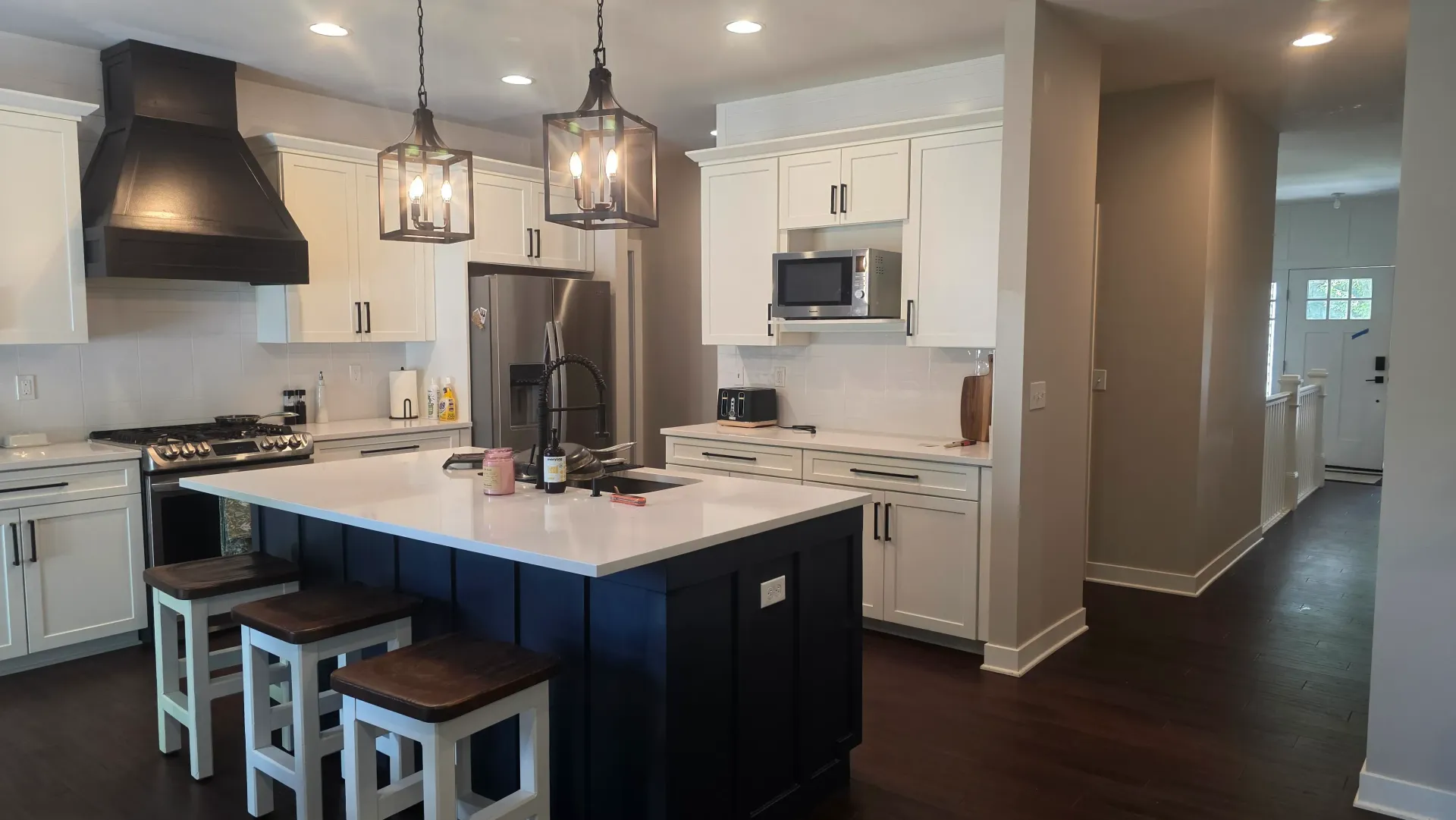 Modern kitchen with white cabinets, dark island, pendant lights, and bar stools
