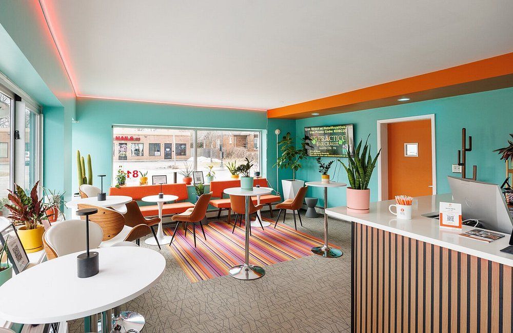 Colorful modern cafe interior with orange chairs, teal walls, and a striped counter by large windows