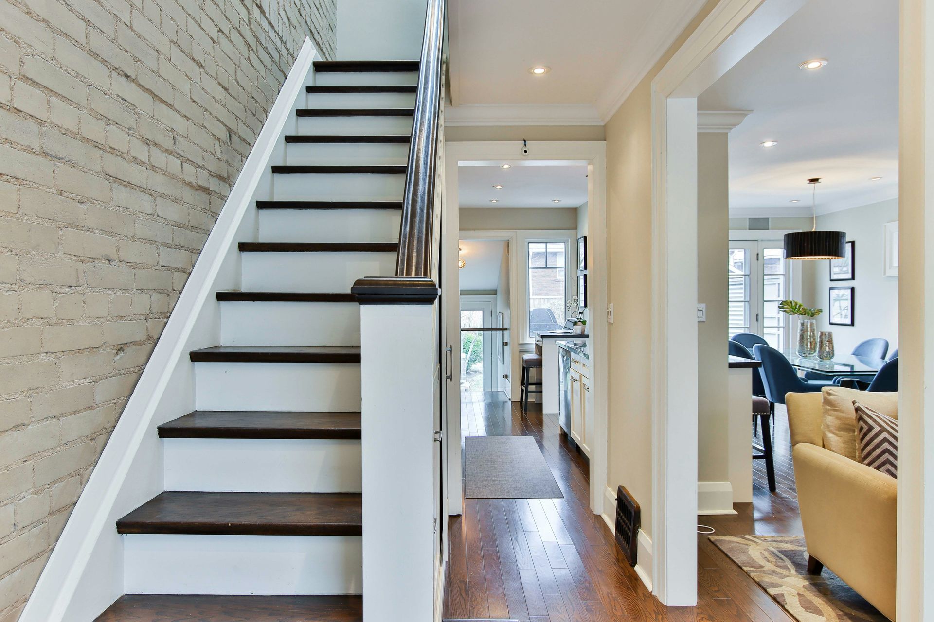 Bright modern hallway with white staircase, wood steps, and open view into a living room