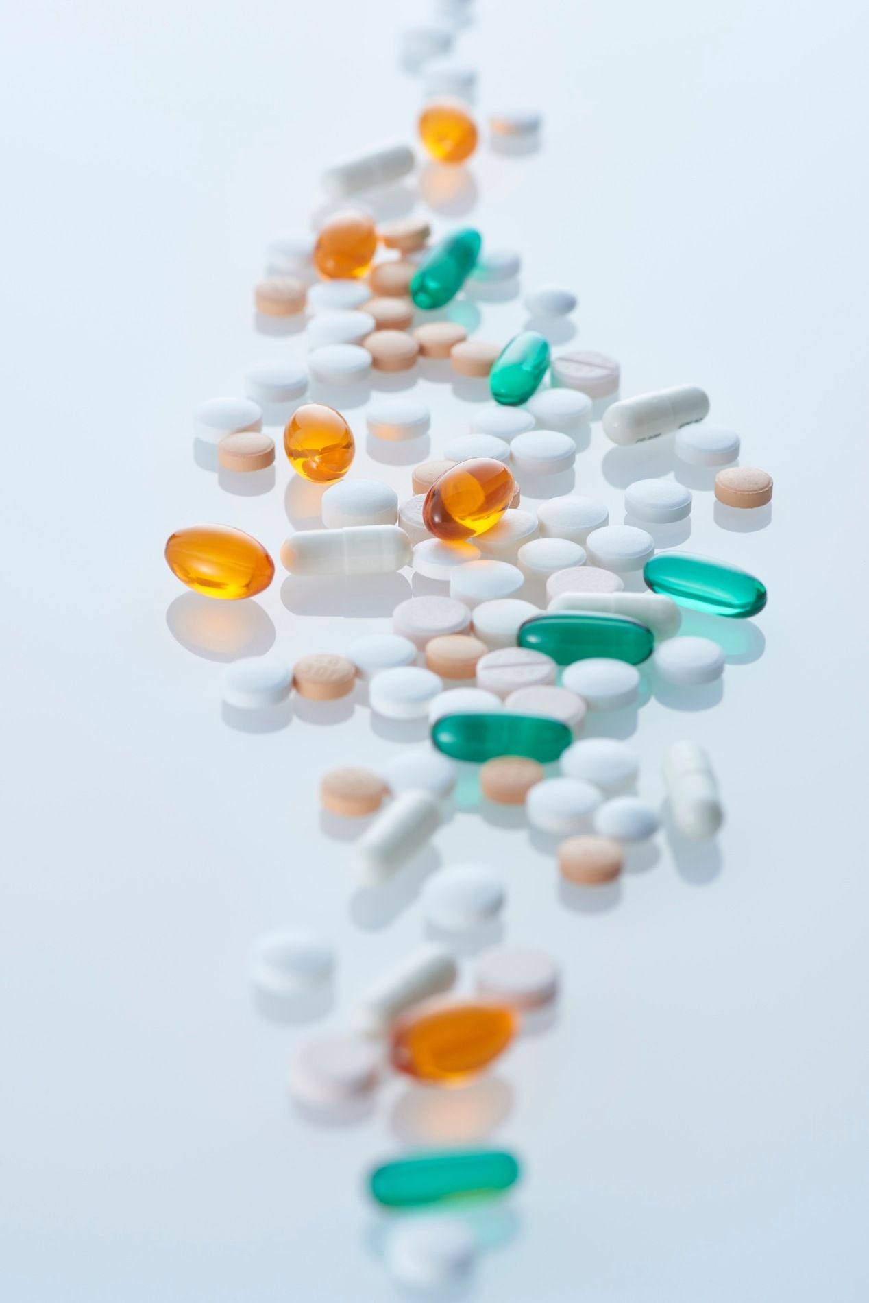 Scattered white, orange, and green capsules on a light background