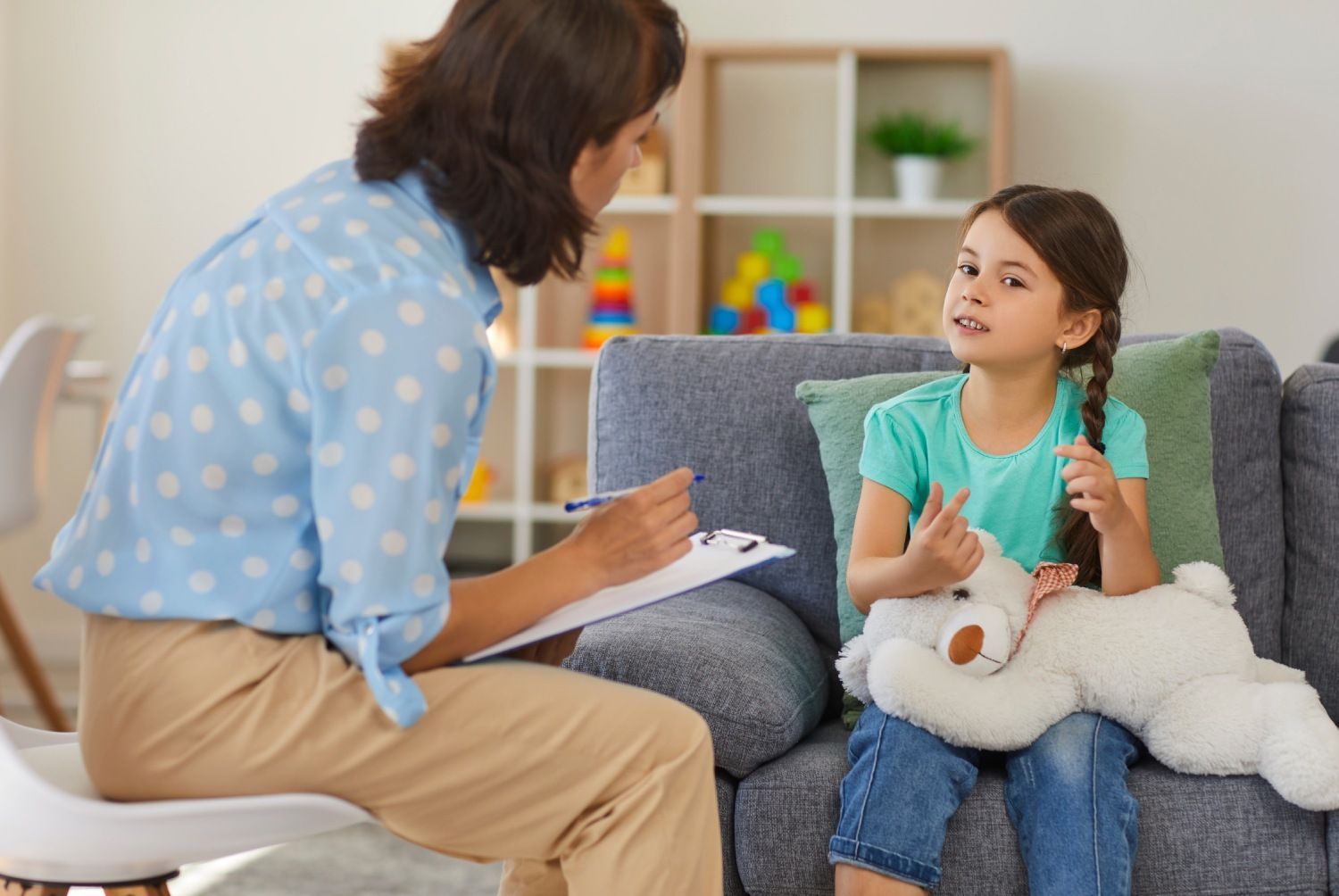 Therapist talking with a child on a sofa during a counseling session