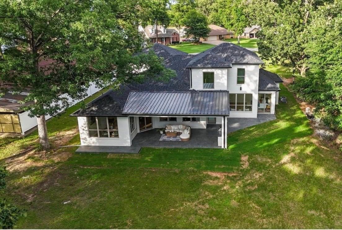 Aerial view of a white two-story house with a dark roof, surrounded by trees and green lawn.