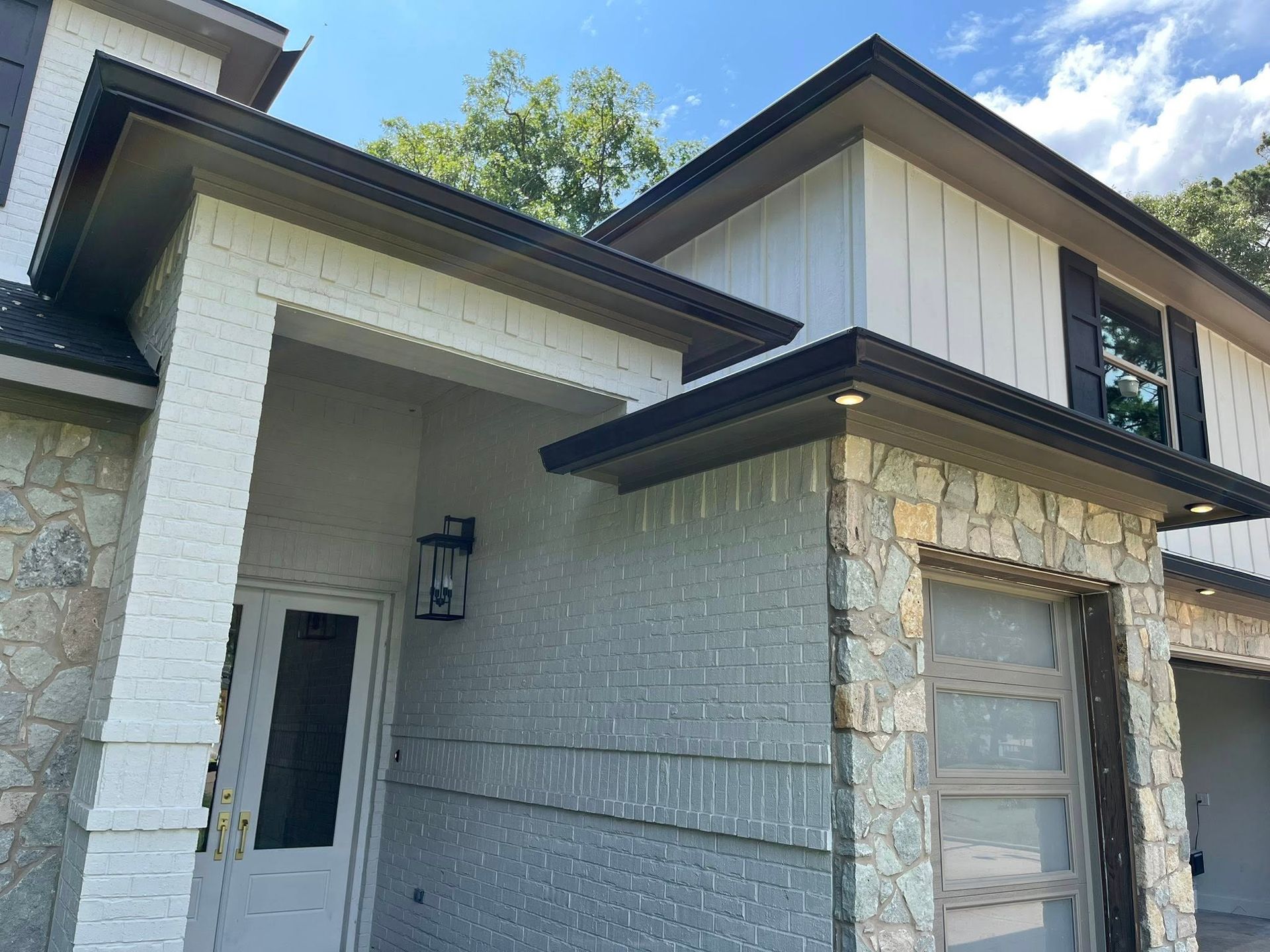 Modern stone-and-white house exterior with a covered entry and upper dormer windows