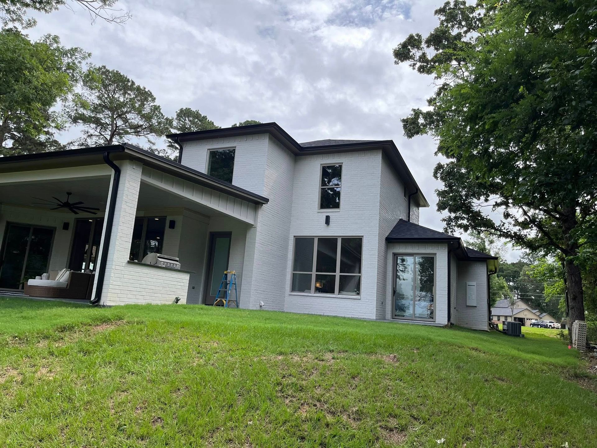 Modern two-story white house with dark trim and a grassy yard under cloudy skies