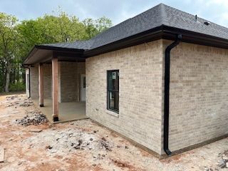 New brick house exterior with dark roof and unfinished dirt yard