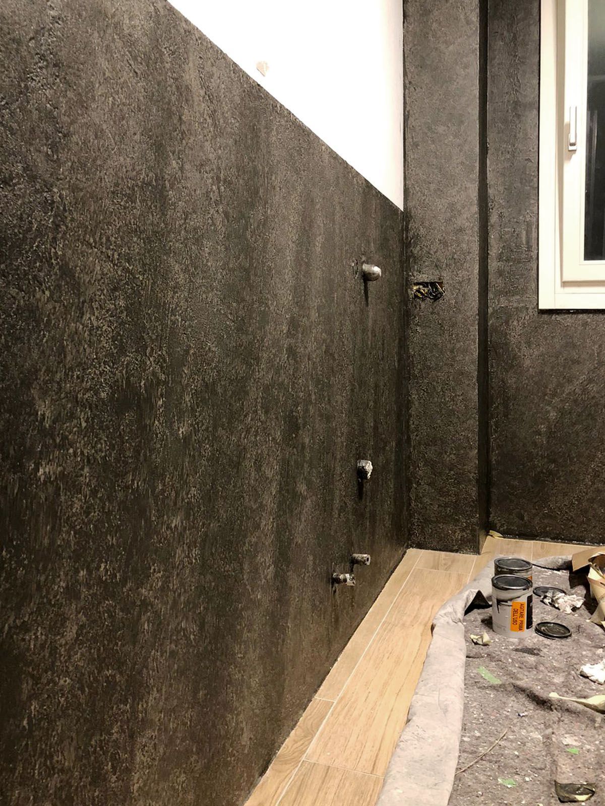 Un bagno con una parete nera e una finestra.