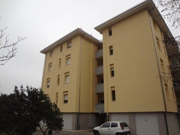 Un edificio giallo con un'auto bianca parcheggiata davanti