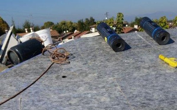 Tre rotoli di materiale di copertura sono appoggiati sul tetto.