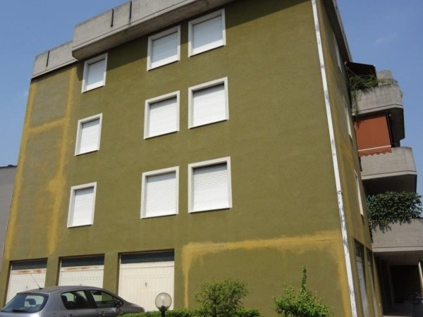 Un edificio verde con un'auto parcheggiata di fronte