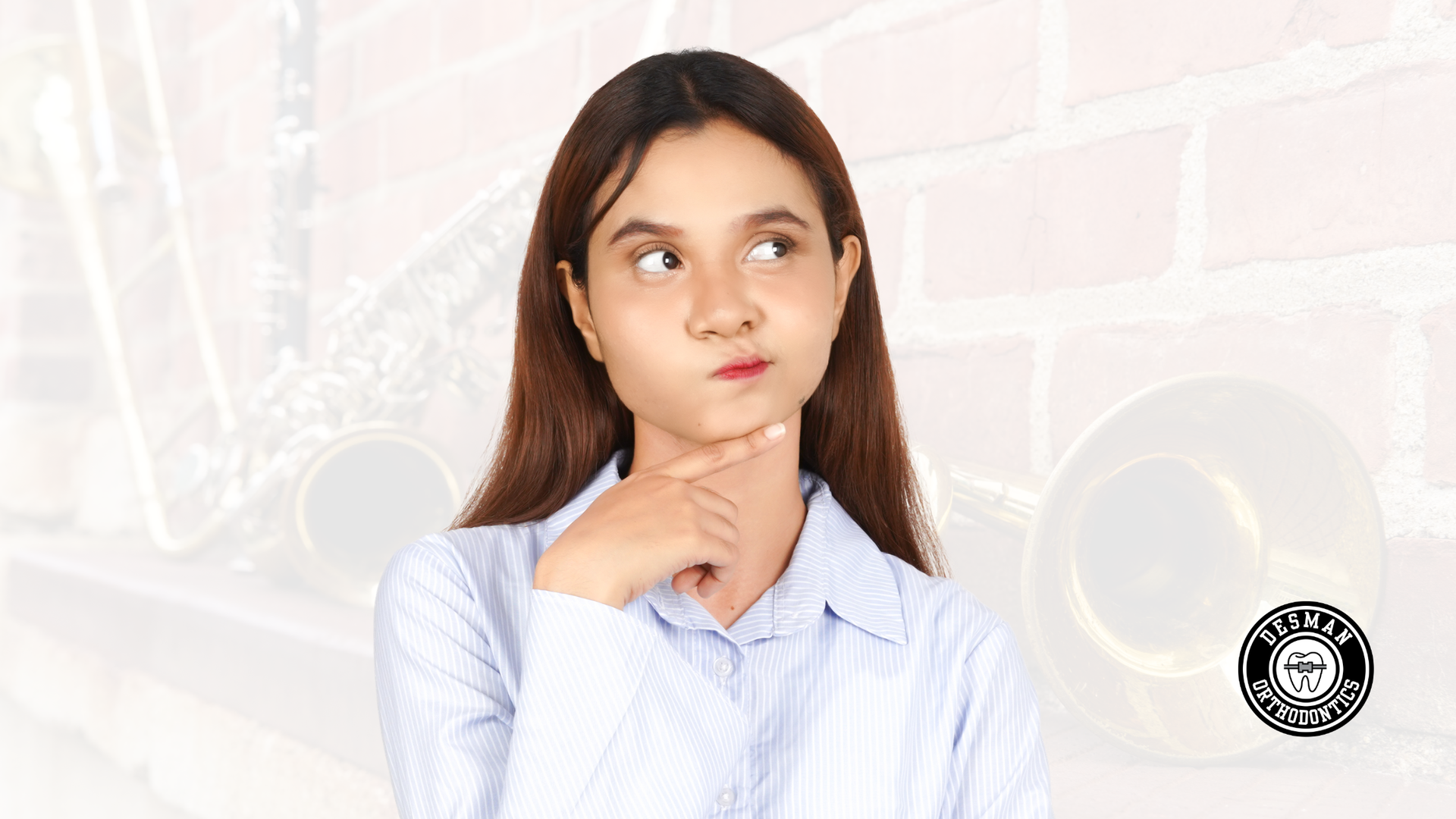 Young person in a white shirt looking up thoughtfully against a light brick wall background